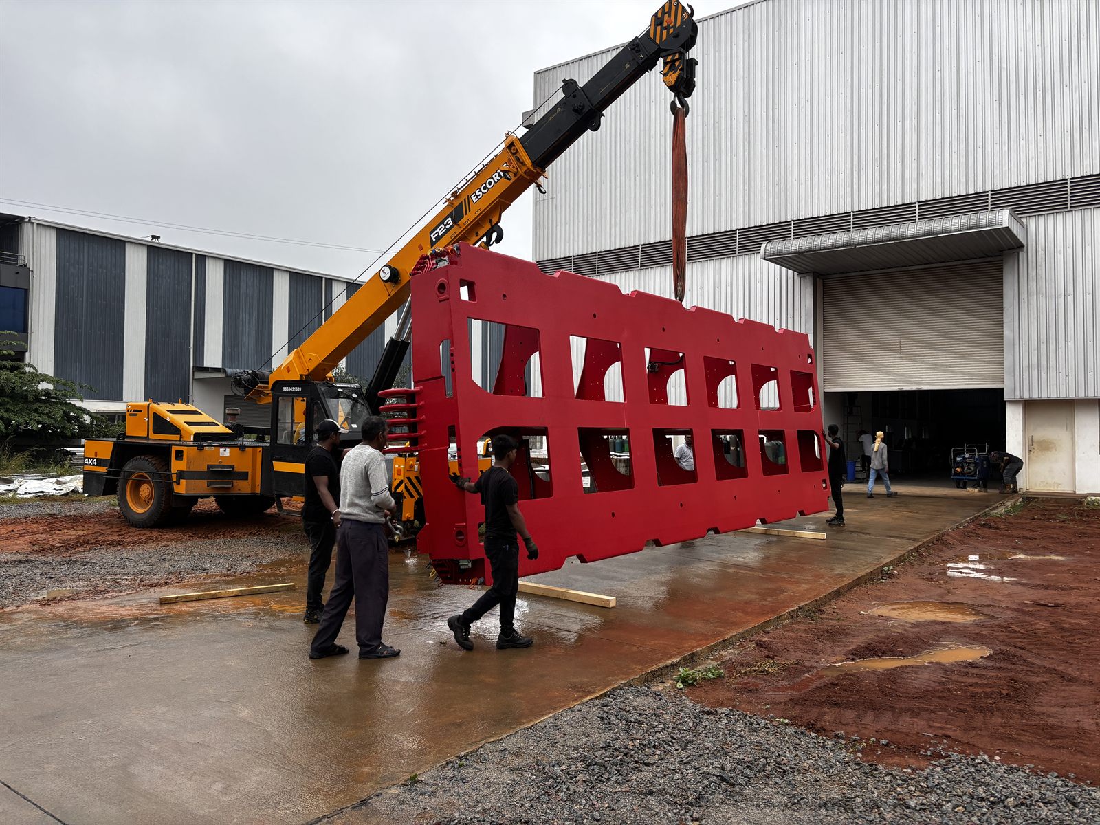 Large fabricated frame lifted by crane outside the facility